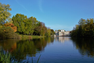 Obraz premium Autumn time in Warsaw's Royal Baths Park (in Polish: Lazienki Krolewskie). Palace on the Water and pond with reflections in the water. Warsaw, Poland