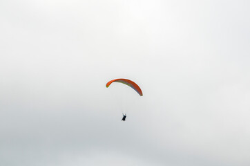 Paraglider silhouette flying in foggy sky in Carpathian mountains. Popular tourist extreme sport...