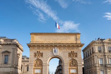 Fototapeta na wymiar The Porte du Peyrou is a triumphal arch in Montpellier, in southern France. It is situated at the eastern end of the Jardin de Peyrou, a park near the center of the city. French flag on the top.