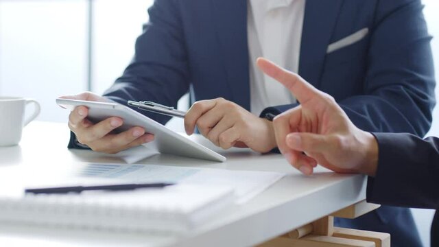 Professional businessman in suit using tablet meeting about business finance, working in office