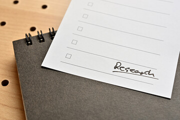 A piece of paper with the word "Research" written on it is placed on top of the notebook.