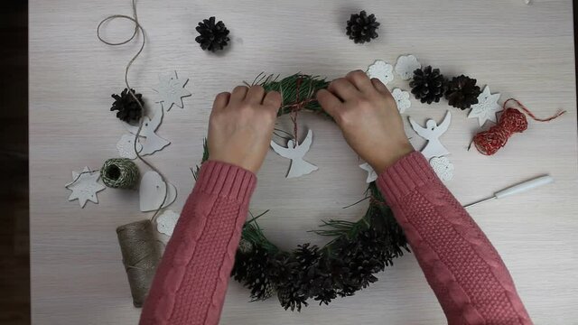 Woman making a fir wreath for Christmas Eve and decorating it with stars and angels with homemade salt dough, diy craft decoration, winter traditions, seasonal holidays. Top view