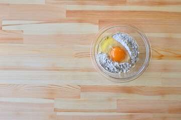 Flour and raw eggs in a glass bowl.