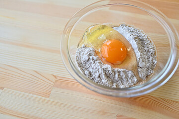 Flour and raw eggs in a glass bowl.