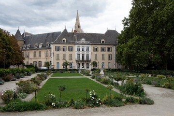 Fototapeta premium View on a square in the city center of Grenoble, in the French Alps. Cloudy sky. Church tower in the background.