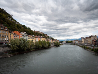 Fototapeta na wymiar View of the Isère River and the Saint-Laurent district on the left. Photographed in Grenoble, a city in the French Alps. Cloudy sky.