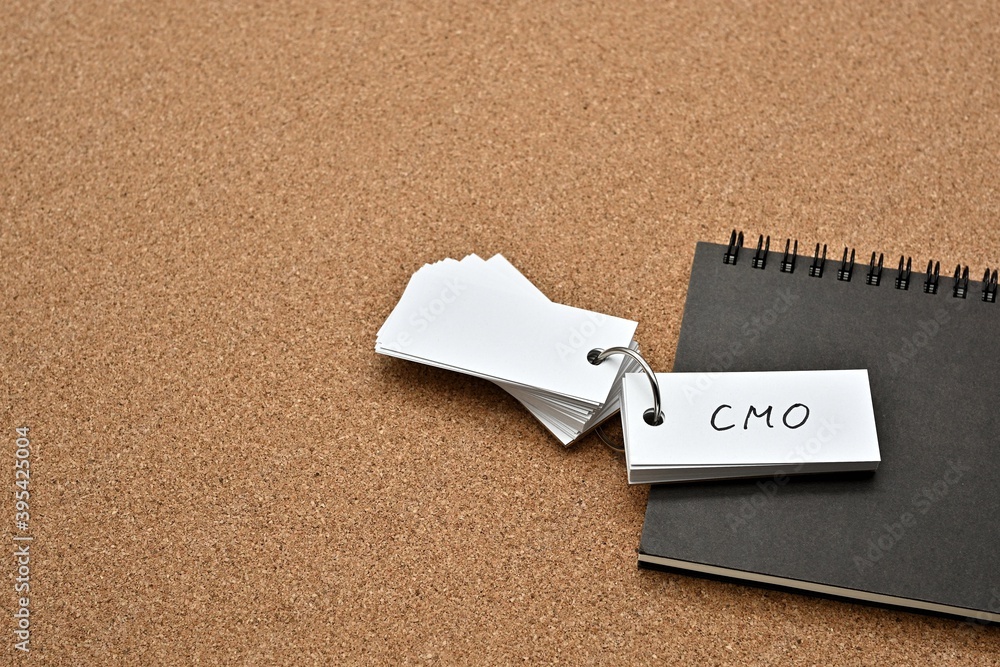 Poster on top of the notebook on the cork board is a wordbook with the word cmo written on it. it means chi