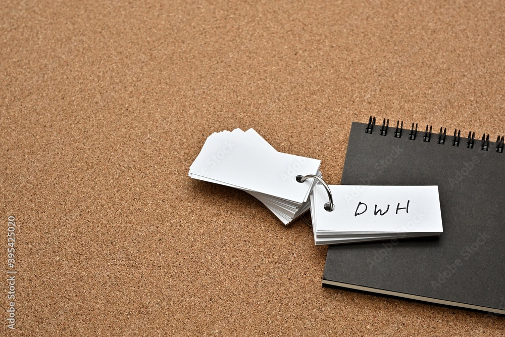 Poster on top of the notebook on the cork board is a wordbook with the word dwh written on it. it means dat