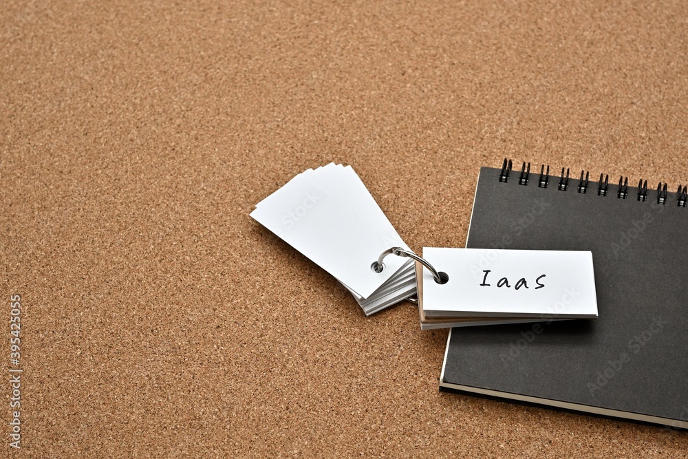 Poster on top of the notebook on the cork board is a wordbook with the word iaas written on it. it means in