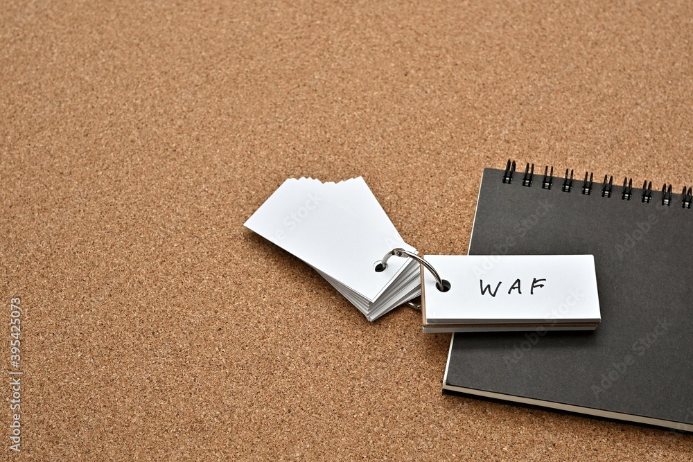 Poster on top of the notebook on the cork board is a wordbook with the word waf written on it. it means web