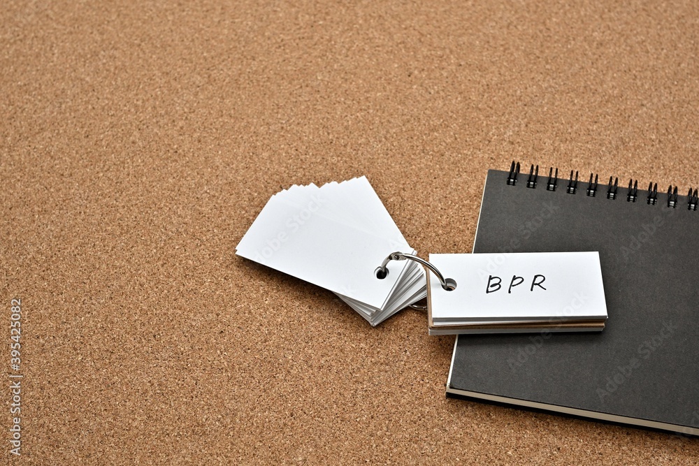 Poster on top of the notebook on the cork board is a wordbook with the word bpr written on it. it means bus