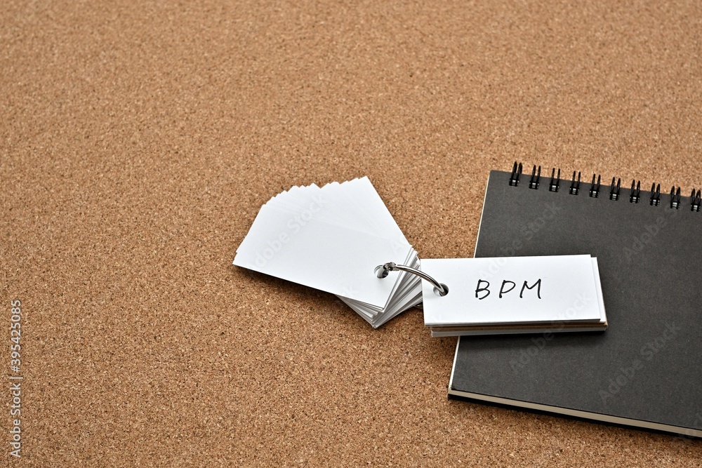 Poster on top of the notebook on the cork board is a wordbook with the word bpm written on it. it means bus