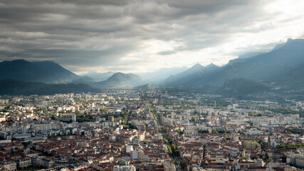 View on the city of Grenoble, Isère, France, from the bastille fortress. Cloudy sky, light in the background.
