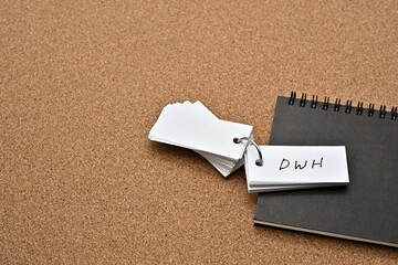 On top of the notebook on the cork board is a wordbook with the word DWH written on it. It means Data WareHouse.