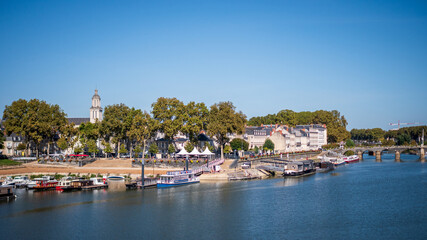 Fototapeta na wymiar Cityscape of Angers, a city located in western France. View on the Maine river. Sunny day, blue sky.