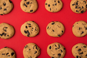Top overhead close up photo of tasty homemade yummy cookies with chocolate chips isolated bright color red background