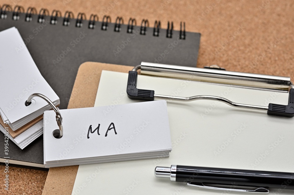 Poster on top of the notebook and clipboard is a wordbook and pen with the word ma written on it. it means 