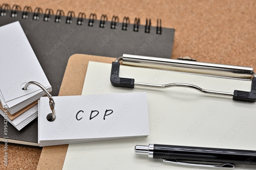 Poster on top of the notebook and clipboard is a wordbook and pen with the word cdp written on it. it means