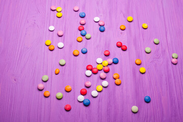 colorful chocolate buttons isolated on a purple board background