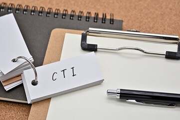 On top of the notebook and clipboard is a wordbook and pen with the word CTI written on it. It means Computer Telephony Integration.