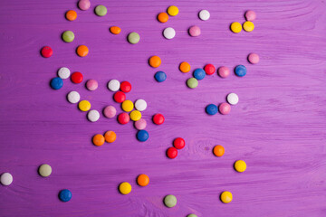 colorful chocolate buttons isolated on a purple board background