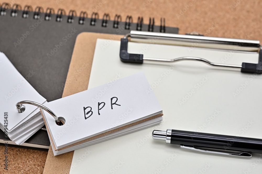 Poster on top of the notebook and clipboard is a wordbook and pen with the word bpr written on it. it means