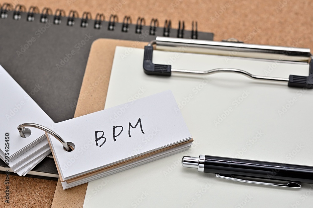 Poster on top of the notebook and clipboard is a wordbook and pen with the word bpm written on it. it means