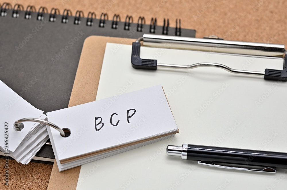 Poster on top of the notebook and clipboard is a wordbook and pen with the word bcp written on it. it means