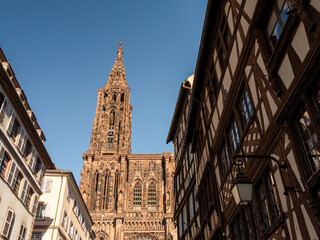 View of the Strasbourg cathedral and its tower from the streets of the old town. Photographed in low angle. Photographed during the summer. Strasbourg is located in Alsace, France.