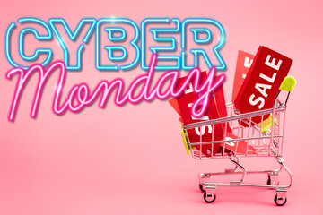 red labels with sale in small shopping trolley near cyber monday lettering on pink, stock image