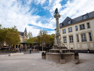 Fototapeta na wymiar The Place d'Armes is a square in Luxembourg City in the south of the Grand Duchy of Luxembourg. Dicks-Lentz monument in the foreground. Cloudy sky. 