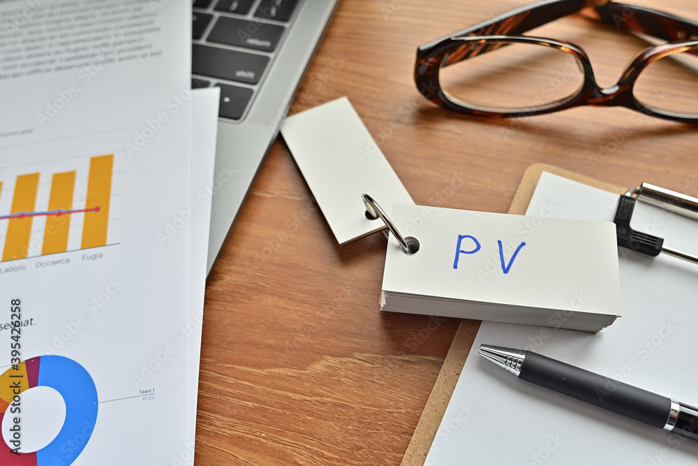 Poster on top of the notebook and clipboard is a wordbook and pen with the word pv written on it. it means 