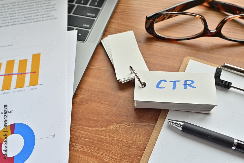 Poster on top of the notebook and clipboard is a wordbook and pen with the word ctr written on it. it means