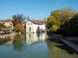 Fototapeta na wymiar City of Annecy, Savoie, France. Sunny day, reflection on the canal. Blue sky, autumn. 