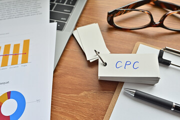 On top of the notebook and clipboard is a wordbook and pen with the word CPC written on it. It...