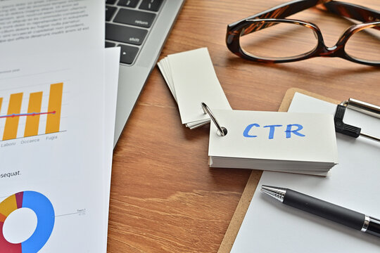 On Top Of The Notebook And Clipboard Is A Wordbook And Pen With The Word CTR Written On It. It Means Click Through Rate.