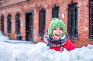 Emotional happy child boy girl playing snowballs outdoors in a snowy city. Winter leisure and children's games. Healthy lifestyle and children's activities. Christmas Holidays