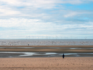 Fototapeta na wymiar the beach at blundell flats in sefton, southport with pools on the beach the beach and the wind turbines at burbo bank visible in the distance