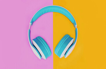 Close up of blue headphones over colorful pink yellow background, top view