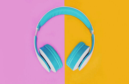 Close up of blue headphones over colorful pink yellow background, top view