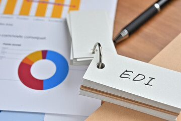 There is a piece of paper with a graph printed on it, a notebook, and an open vocabulary book on the desk. The word EDI is there. It's an acronym that means Electronic Data Interchange.