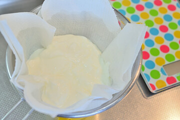 Draining the yogurt on a colander to make a yogurt cake.