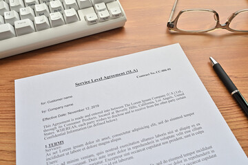 There's a keyboard, notebook, glasses, and a "Service Level Agreement (SLA)" paper (it's dummy) on the desk.