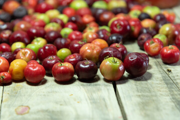 Cowberry fruits (Malpighia emarginata) on wooden background in selective focus
