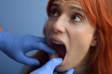 
Doctor examines the braces of the woman's bosom while she looks at him scared