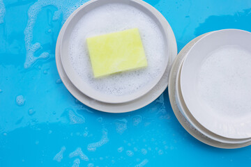 Washing dishes concept on wet blue background. Top view