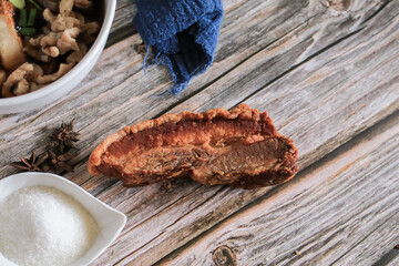 Thai crispy skin pork belly or deep fried pork with chili powder and sugar on wooden table - Asian food style.