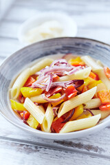 Penne pasta with yellow and red pepper, hard cheese and fresh basil. Bright background. Close up. 