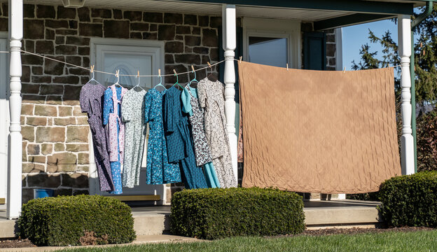 Calico dresses drying on clothesline on front porch of farmhouse