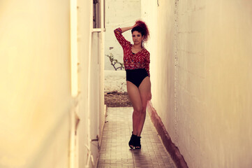 Professional red hair model posing between walls, dressed in colorful blouse and ballerina clothes and shoes with high heels, with the monkey holding her hair